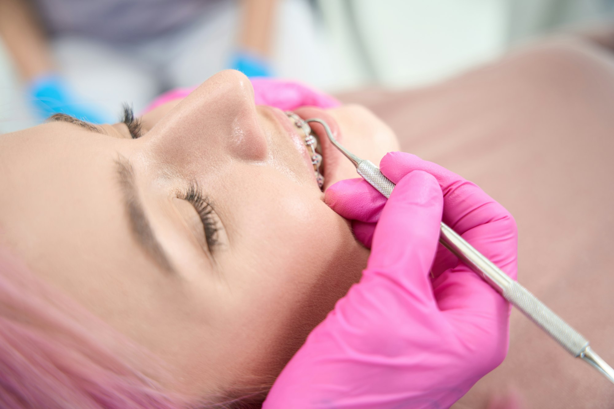 Orthodontist performs maintenance of bracket system for aligning dentition